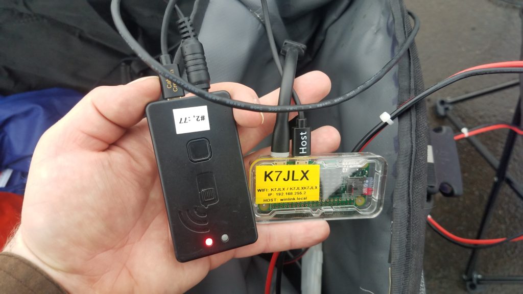 Hand holding the Mobinlinkd TNC3 and Raspberry Pi Zero W connected to each other. Radio data connector is also set up.