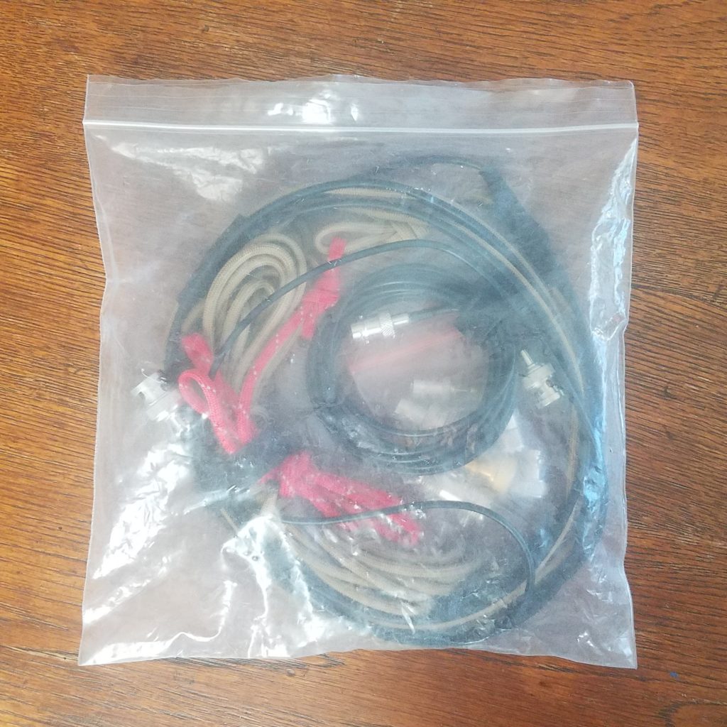Plastic bag containing a roll-up J-pole antenna and various adapters