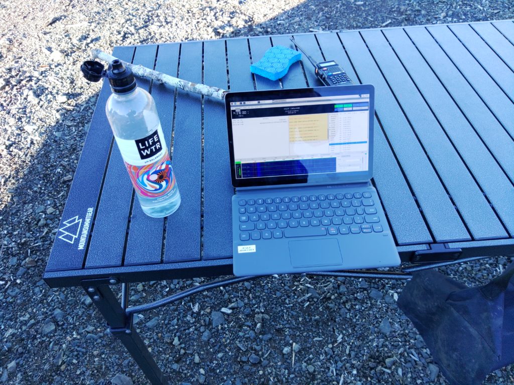 A tablet sitting on a metal camping table running the JS8Call application.