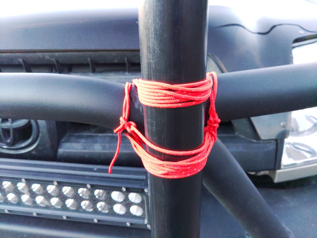Close-up of paracord tying the the antenna mast to steel tubing on an offroading bumper.